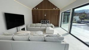 a living room with a white couch and a flat screen tv at Deluxe home garden and pool optional pm in Kortenberg