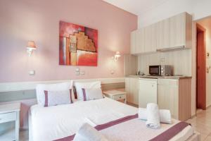 a bedroom with a white bed and a kitchen at Nontas Home 25 in Kalamitsi