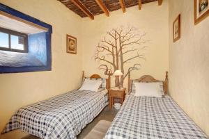 two beds in a room with a tree mural on the wall at Casa Rural Madre Nieves in Fasnia