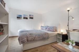 a white bedroom with a bed and a table at De lütt Stuf - Urlaub mit Hund in Born