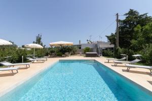 a swimming pool with chairs and umbrellas next to it at Corallo House in Polignano a Mare