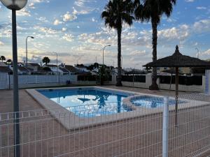 a swimming pool with a fence and palm trees at Rodalia in El Verger