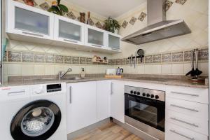a kitchen with white cabinets and a washer and dryer at Casa Alisios in Costa Calma