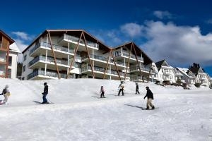 a group of people skiing in the snow in front of a building at Wellnessappartement Winterberg D4 in Winterberg