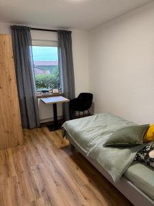 a bedroom with a bed and a desk and a window at Ahlers am Wald in Edewecht