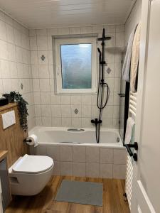 a bathroom with a tub and a toilet and a window at Ahlers am Wald in Edewecht