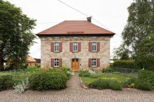 an old brick house with red shutters on it at Tinyhaus am Bussen in Unlingen