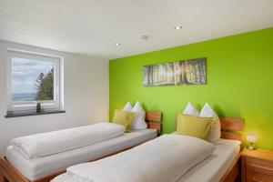 two beds in a room with a green wall at Bäuerleshütte in Breitnau