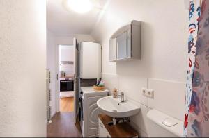 a small white bathroom with a sink and a refrigerator at Apartmenthaus Ferienwohnungen Sila in Weinstadt +65 photos