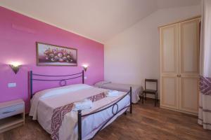 a bedroom with a bed and a purple wall at Casa Ginestre piscina e vista mare in Aglientu