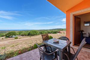 a table and chairs on a patio with a view of a field at Casa Ginestre piscina e vista mare in Aglientu