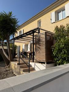 a building with a patio with a table and a tree at Appartement deux chambres spacieux avec jardin et entièrement privatif dans lotissement très calme in Biguglia