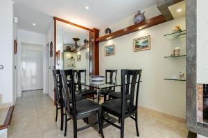 a dining room with a glass table and black chairs at Ca la Montse in Altafulla