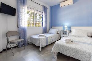 a bedroom with two beds and a chair and a window at Milestone House in Rincón de la Victoria +20 photos