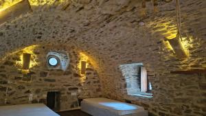 a room with a stone wall with a bed and a window at Pyrgos Mitsakou 2 in Vathia