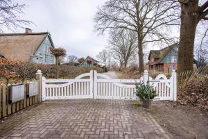 a white fence in front of a driveway at Ferienwohnung Gestüt Kriseby in Lübeck