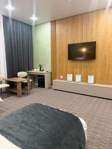 a hotel room with a bed and a flat screen tv at Essenali in Taraz