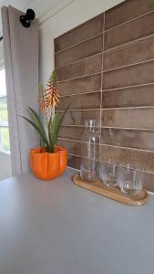 Eine orangefarbene Vase stand auf einem Tisch mit drei Gläsern. in der Unterkunft Westerhoeve in Petten