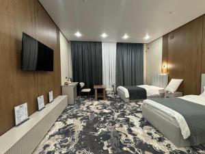 a hotel room with two beds and a flat screen tv at Essenali in Taraz