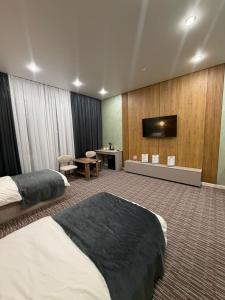 a hotel room with two beds and a flat screen tv at Essenali in Taraz +18 photos