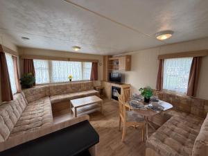 a living room with a couch and a table at Sunnymede G20 with Hot Tub - pet friendly, Wifi, bed linen - Meadow Lakes Caravan & Lodge Hire in Ingoldmells