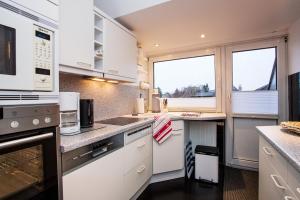 a kitchen with white cabinets and a large window at Haus Schulz in Heide