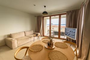 a living room with a table and a couch at Kožino Bay Lodge - Brand New Seaside Apartments, Heated Pool in Kožino