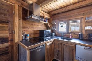 a kitchen with a stove and a sink in a log cabin at Mazot des aravis in Combloux