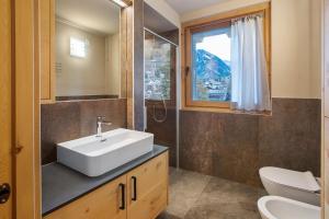 ein Badezimmer mit Waschbecken, Toilette und Fenster in der Unterkunft Quattropassi Bormio in Bormio + 55 Fotos