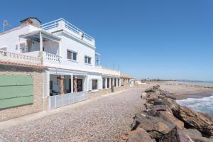 a white building on a rocky beach with the ocean at Casacamer S in Sagunto