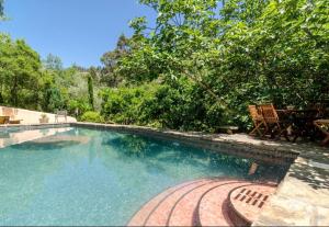 a swimming pool with two chairs and a table at Casa Cisne - Selão da Eira in São Miguel