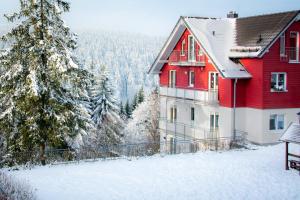 a red and white house in the snow at Ferienwohnung Tannenblick 8-1 in Oberhof