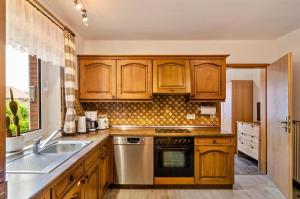 a kitchen with wooden cabinets and a sink at Haus Störtebeker in Marienhafe