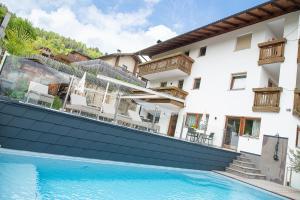 a hotel with a swimming pool in front of a building at Hotel Klausthaler in Meltina