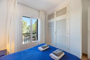 a bedroom with a blue bed and a window at Apartamento Isla Blanca in Es Pujols