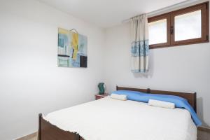 a white bedroom with a bed and two windows at Il Giglio in Cardedu