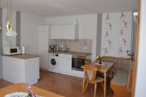 a kitchen with white cabinets and a table and a dining room at Ferienwohnung Meins in Friesoythe +8 photos