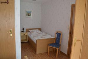 a small bedroom with a bed and a blue chair at Ferienwohnung Meins in Friesoythe