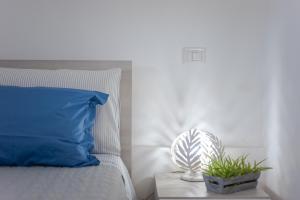 a bed with a blue pillow and a plant on a night stand at Casa Petunia in Sarroch