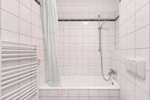 a white tiled bathroom with a shower and a tub at Albrechtshof Apartment 3 in Potsdam +19 photos