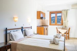 a bedroom with two beds and a table at Petra Studios in Karpathos