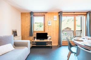a living room with a couch and a television at Charmant Duplex Au Pied Des Pistes in Albiez-Montrond