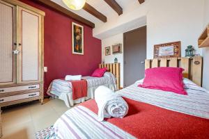 a bedroom with two beds and a red wall at Priorat Tranquil in Lloá
