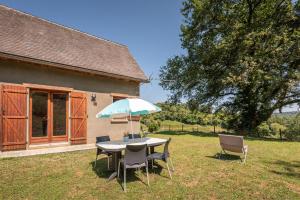 a table with chairs and an umbrella in a yard at Gite Lieuj in Peyrouse