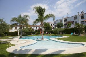 a swimming pool with palm trees and a building at Villa Consuelo in Cambrils