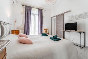 a bedroom with a bed with pink pillows and a tv at Le Mas de Kitty - Maison d'hôtes in Saint-Rémy-de-Provence