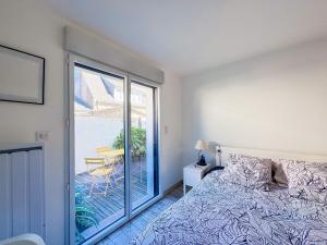 a bedroom with a bed and a sliding glass door at Les Embruns - Vue sur mer in Île-Tudy