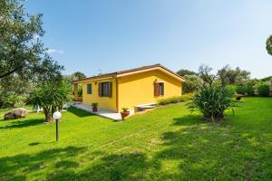 a small yellow house in a grassy yard at Casa Mameli in Quartucciu