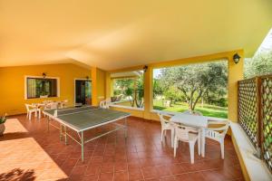 a screened porch with a ping pong table and chairs at Casa Mameli in Quartucciu