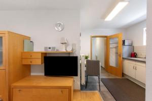 a kitchen and a living room with a desk and a television at Ferienwohnung Emilia, 36qm in Münsingen +19 photos